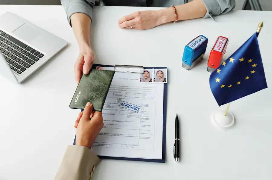A passport being handed over a visa application form on a desk