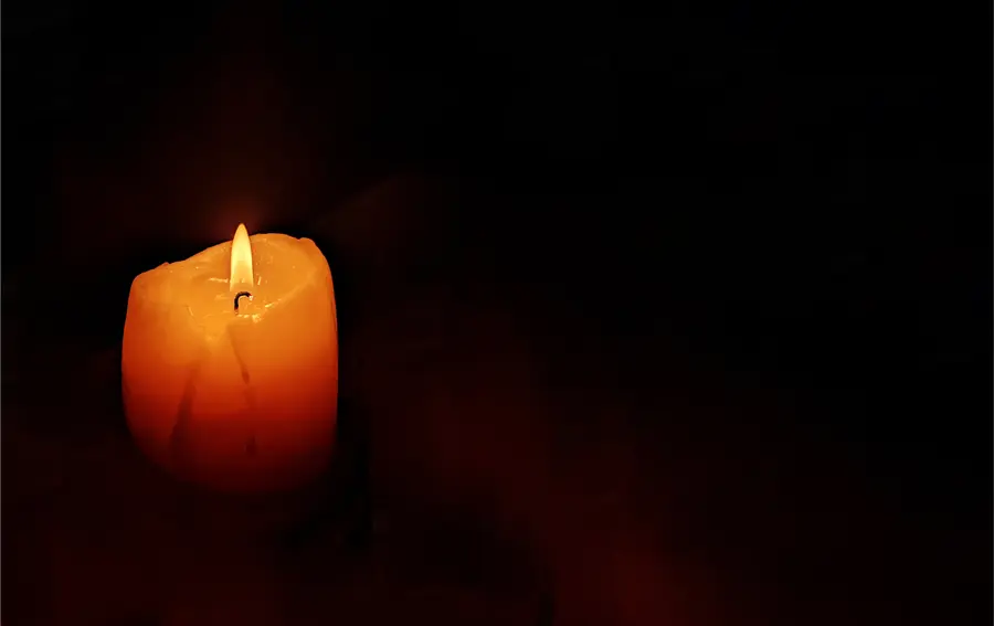 A single lit candle in the dark