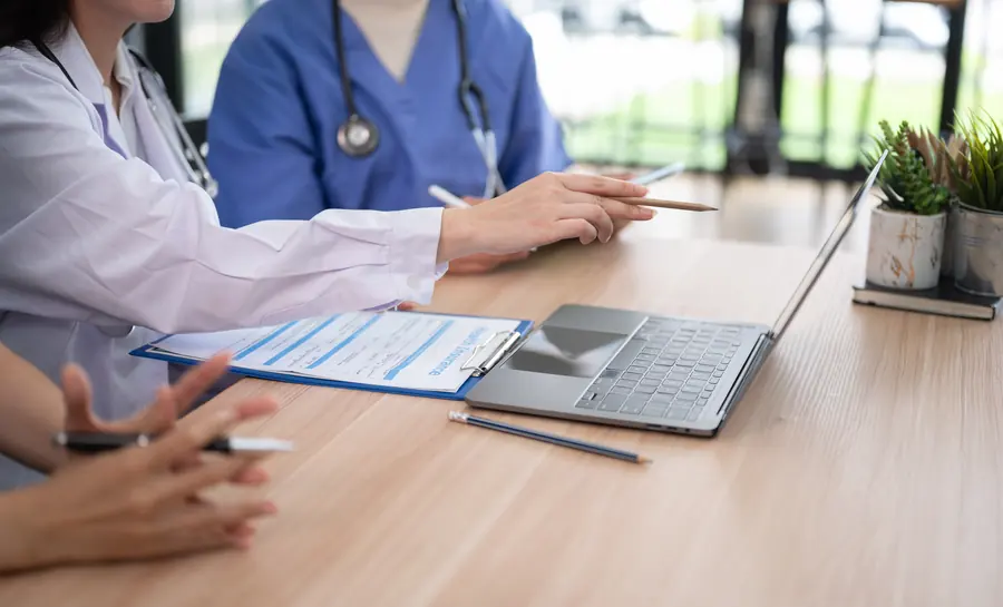 A doctor pointing at a health insurance form while colleagues look on